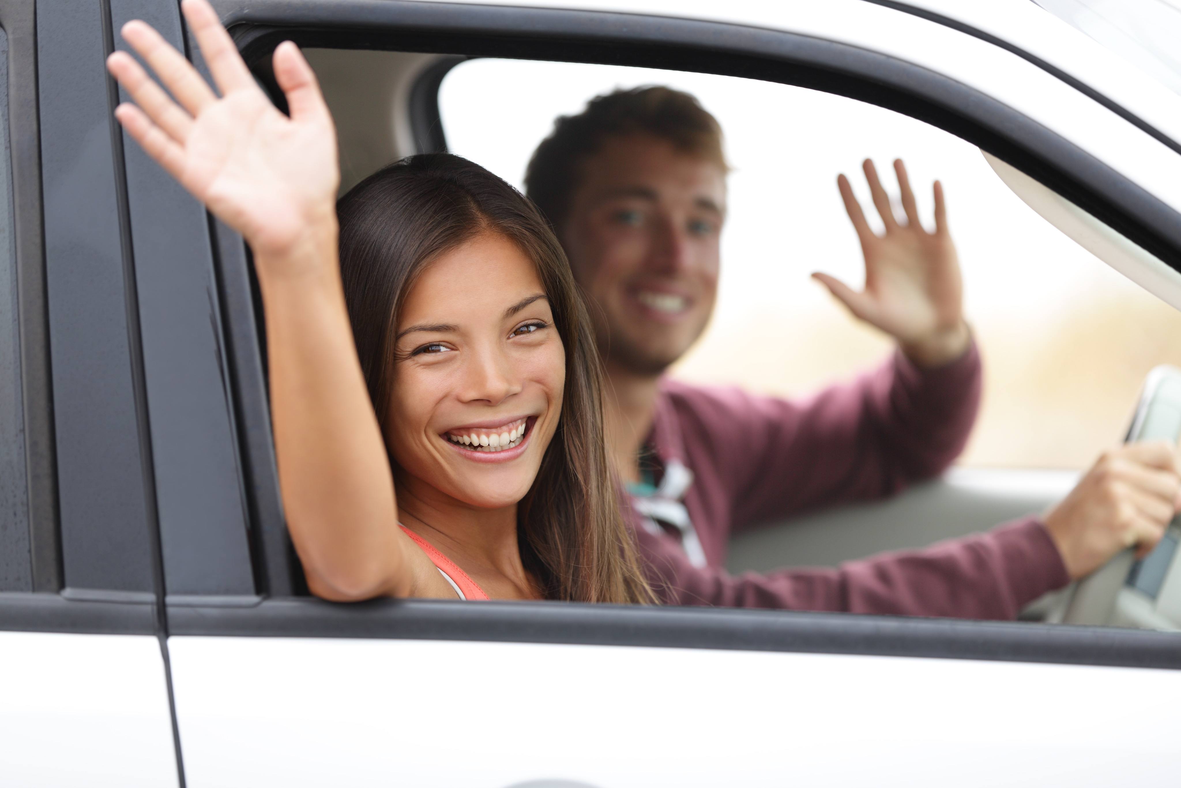 Happy couple in car waving Happy couple in car waving